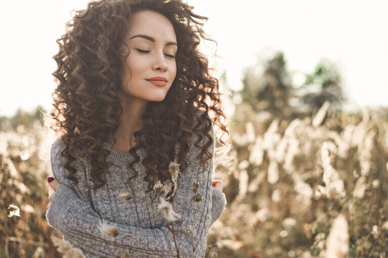 Foto al aire libre de una joven con cabello y ojos marrones, que refleja la calidez y la suavidad del otoño.